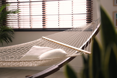 Photo of Comfortable net hammock with pillows in stylish room. Interior design