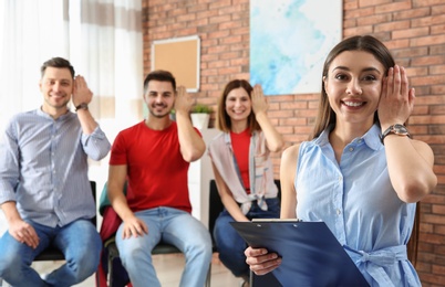 Young teacher showing sign language gesture against blurred background