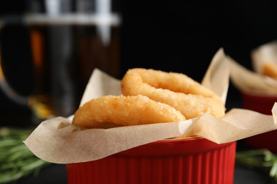 Photo of Fried onion rings on black background, closeup