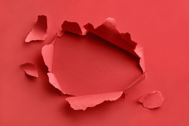 Photo of Hole in red paper on color background
