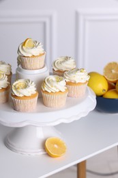 Photo of Delicious lemon cupcakes with cream on white table