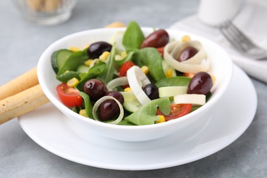 Bowl of tasty salad with leek and olives on grey table, closeup