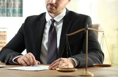 Male notary stamping document at table, closeup