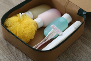Photo of Cosmetic travel kit in compact toiletry bag on wooden table, closeup. Bath accessories