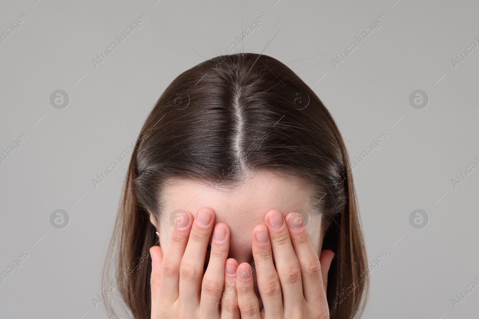 Photo of Woman suffering from hair loss problem on grey background, closeup