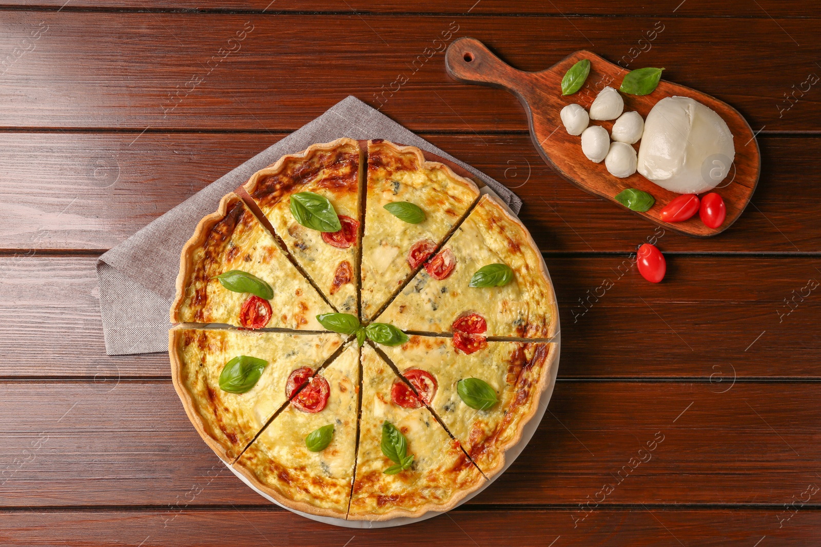 Photo of Delicious homemade cheese quiche and ingredients on wooden table, flat lay