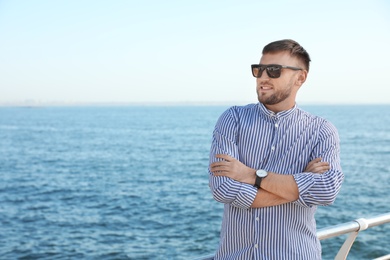 Portrait of handsome young man on sea pier. Space for text