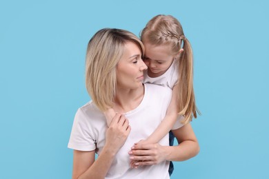 Family portrait of mother and daughter on light blue background