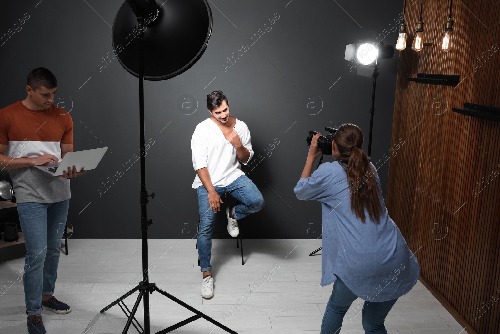 Photo of Professional photographer with assistant taking picture of young man in modern studio