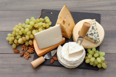 Photo of Different types of delicious cheeses and snacks on wooden table, above view