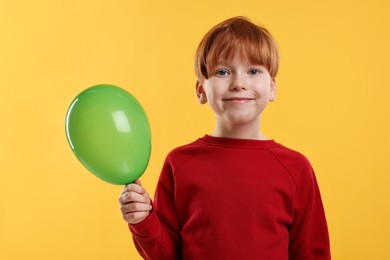 Boy with green balloon on orange background