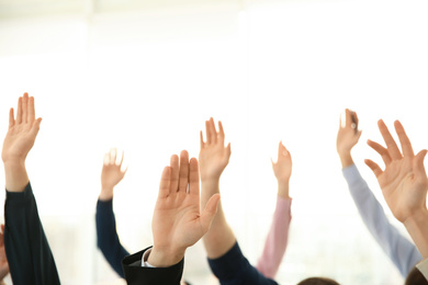 Photo of People raising hands to ask questions at business training on light background, closeup