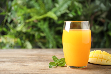 Fresh delicious mango drink on wooden table. Space for text