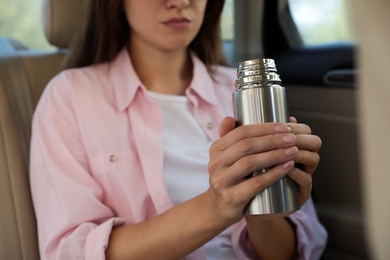 Photo of Woman with thermos inside of car, closeup