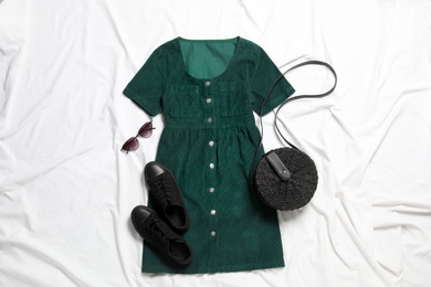 Photo of Flat lay composition with stylish green dress on white fabric