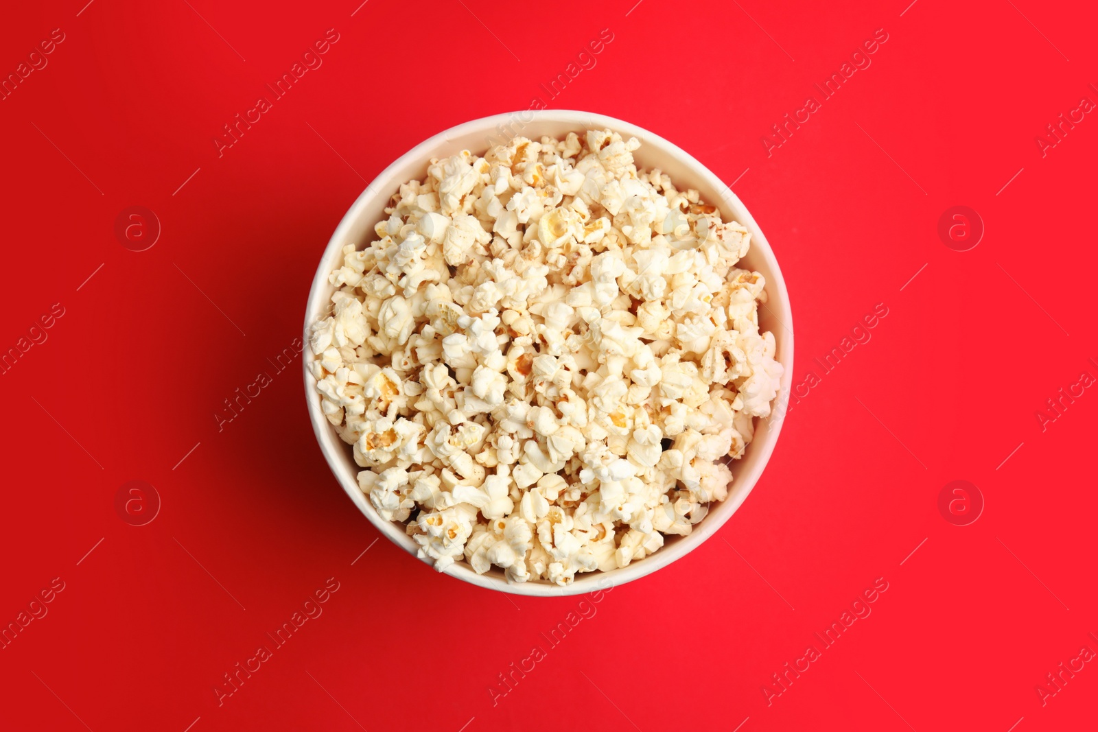 Photo of Tasty pop corn on red background, top view