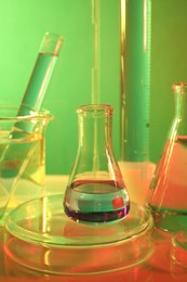 Photo of Laboratory analysis. Different glassware on table against color background, closeup