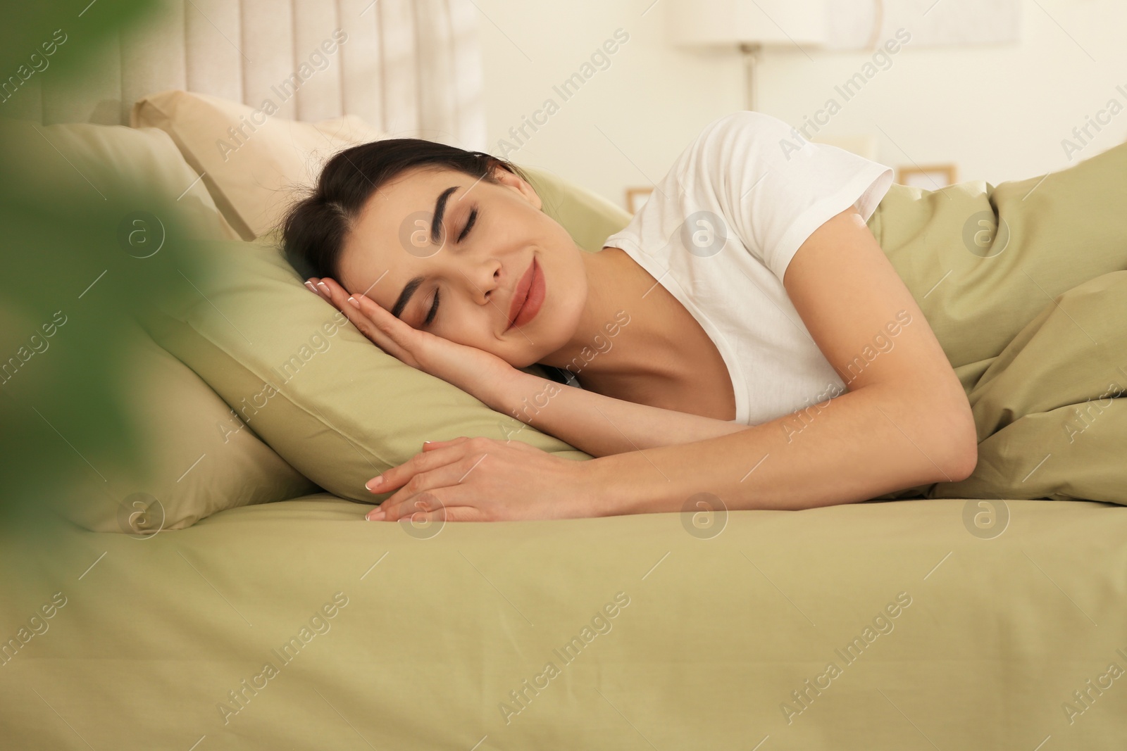 Photo of Young woman sleeping in bed with green linens at home