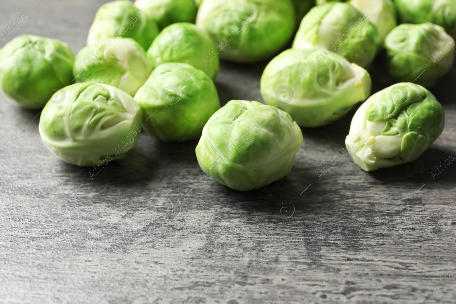 Photo of Fresh Brussels sprouts on grey table, closeup