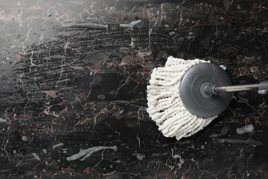 Photo of Cleaning black marble floor with string mop, top view. Space for text