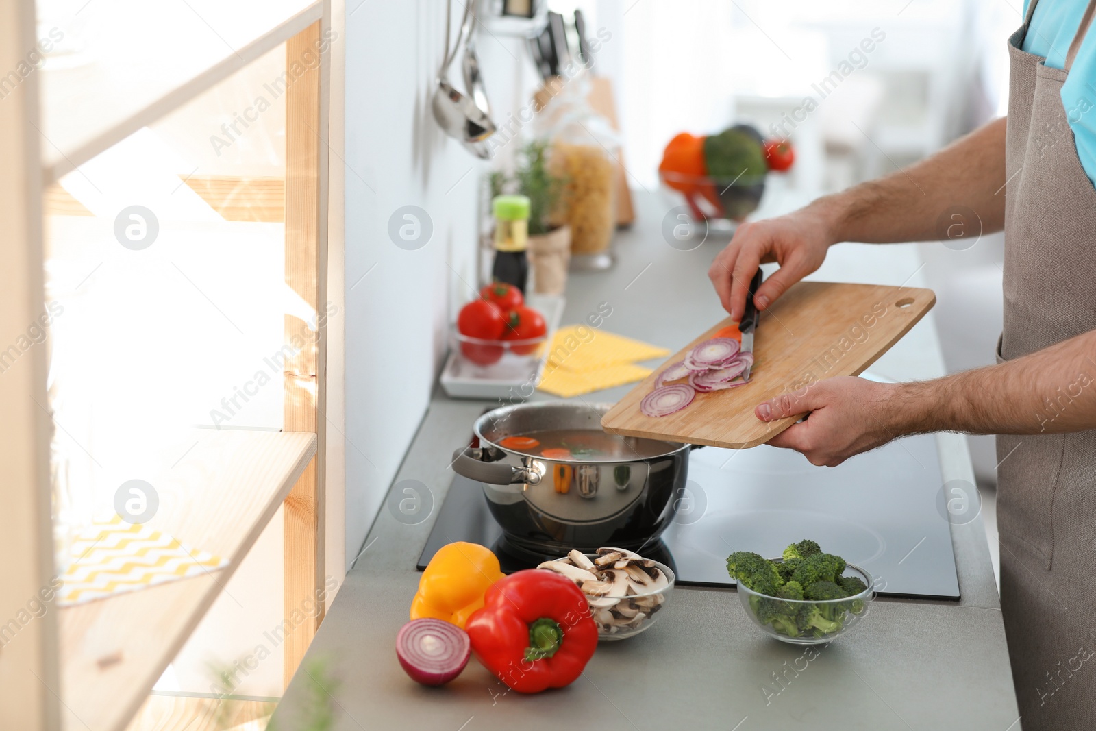 Photo of Young man cooking delicious vegetable soup in kitchen, closeup