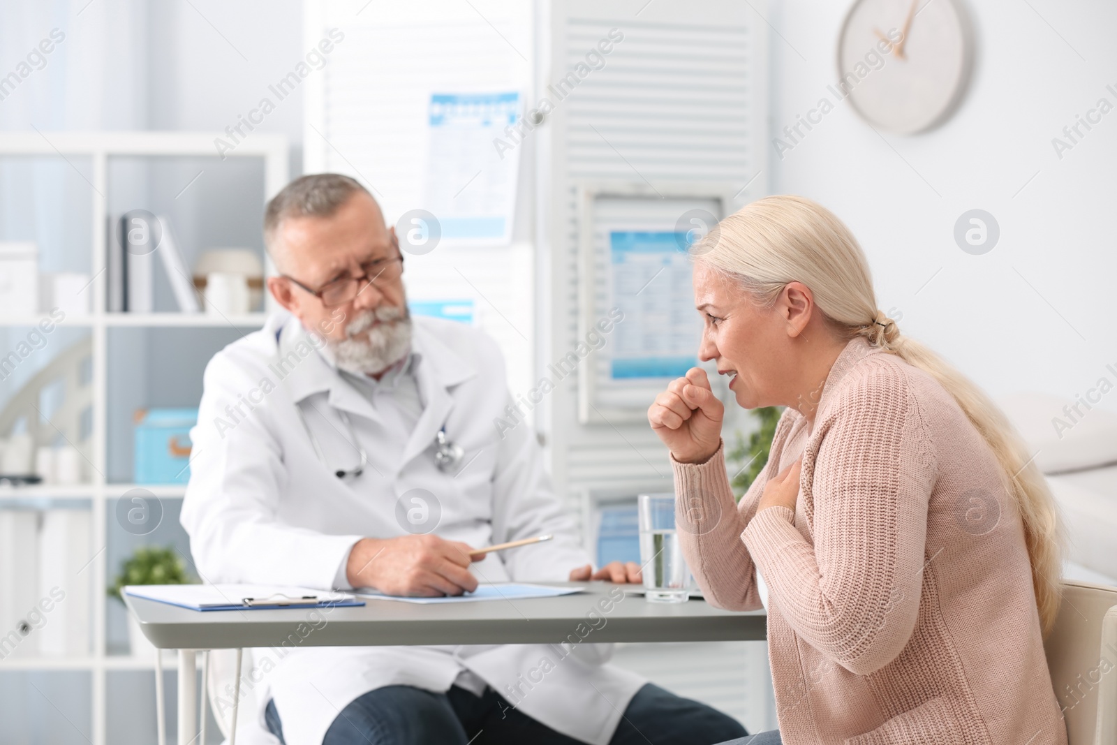 Photo of Coughing mature woman visiting doctor at clinic