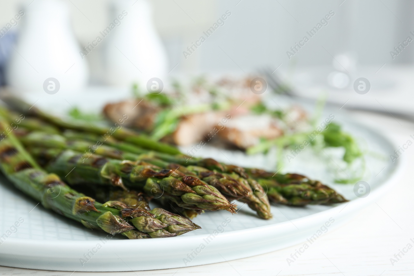 Photo of Tasty grilled asparagus served on plate, closeup