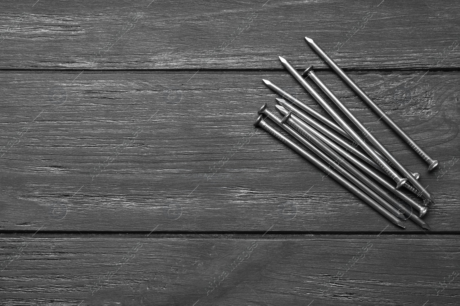 Photo of Pile of metal nails on grey wooden background, flat lay. Space for text