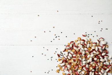 Mixed vegetable seeds on white wooden background, flat lay