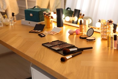 Different cosmetic products on wooden dressing table in makeup room