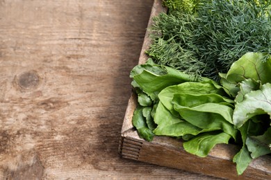 Photo of Fresh green herbs in crate on wooden table. Space for text
