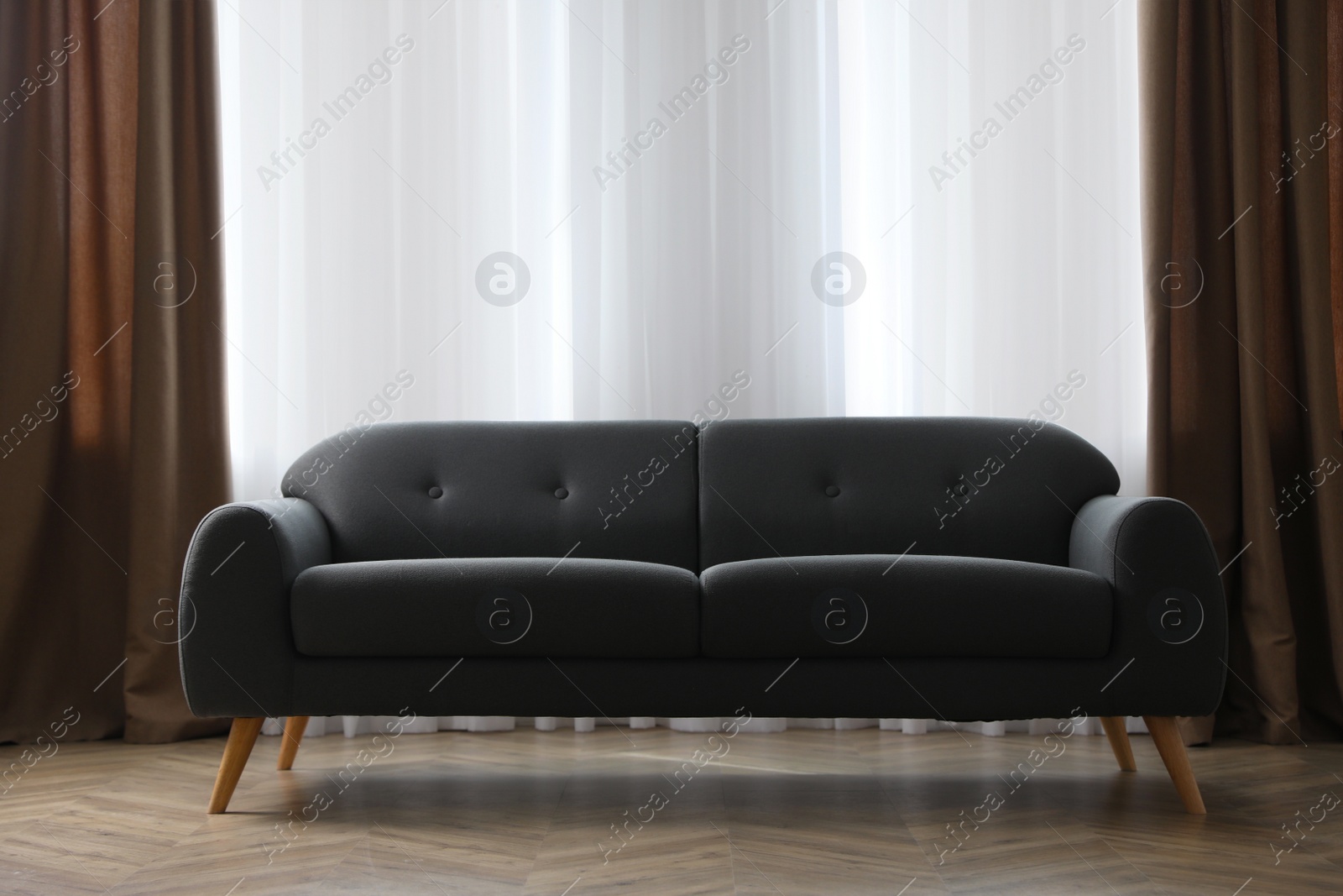 Photo of Comfortable grey sofa near window indoors. Interior design