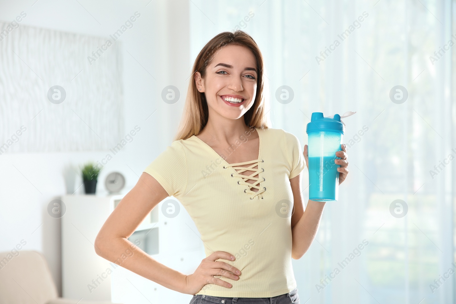 Photo of Young woman with bottle of protein shake at home