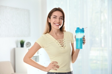 Young woman with bottle of protein shake at home