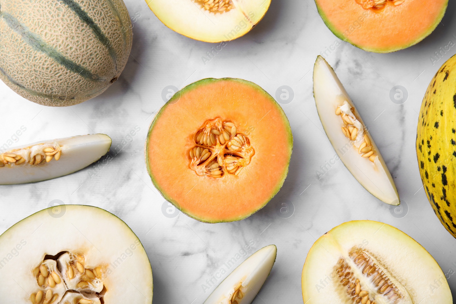 Photo of Tasty colorful ripe melons on white marble table, flat lay