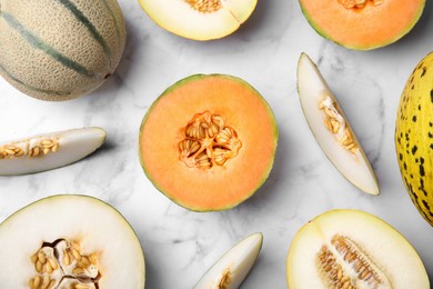 Tasty colorful ripe melons on white marble table, flat lay