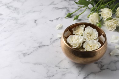 Tibetan singing bowl with water and beautiful roses on white marble table, space for text