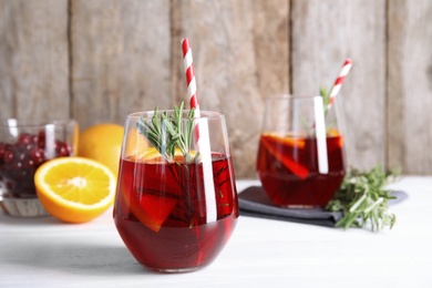 Photo of Tasty refreshing cranberry cocktail with rosemary on table