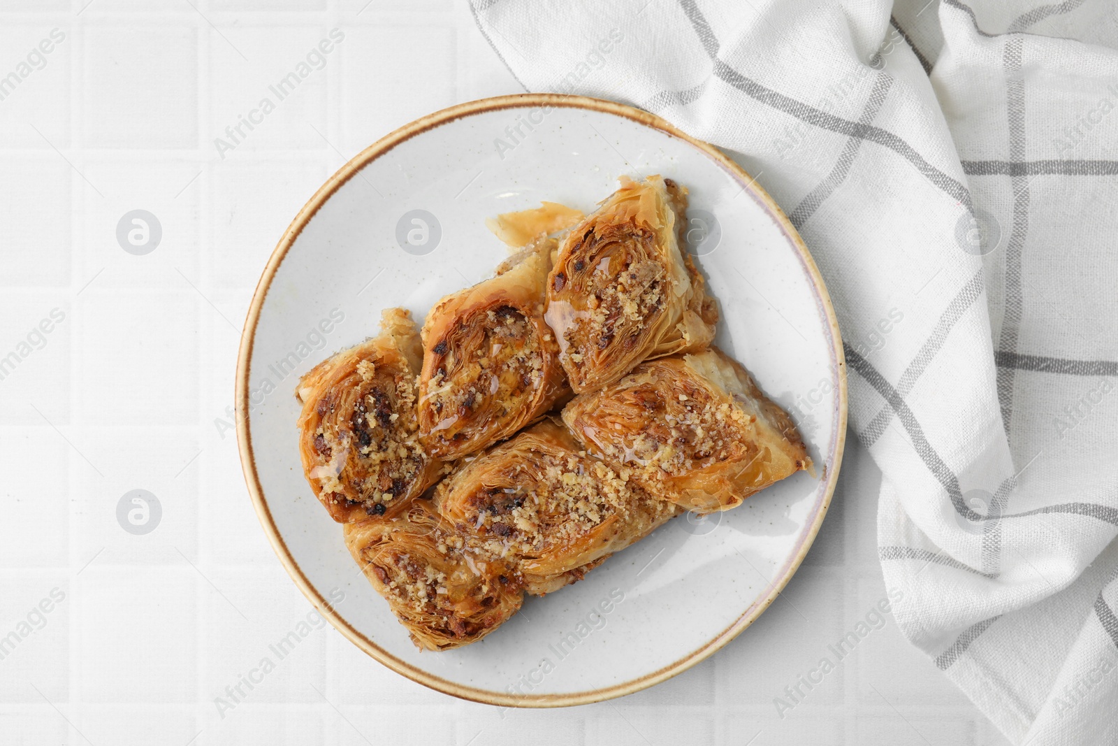 Photo of Eastern sweets. Pieces of tasty baklava on white tiled table, top view