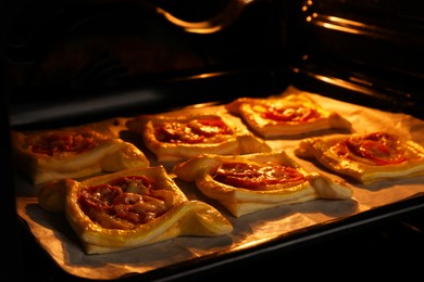 Photo of Baking sheet of puff pastry with tasty filling in oven, closeup