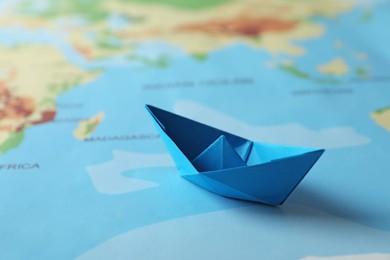 Photo of Light blue paper boat on world map, closeup