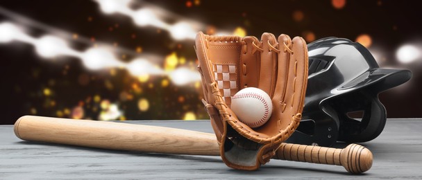 Baseball bat, glove, helmet and ball on wooden table at stadium, banner design