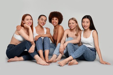 Photo of Group of beautiful young women sitting on light grey background