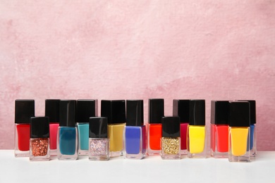 Photo of Bright nail polishes on table against color background. Space for text