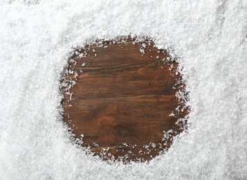 Photo of Frame made with snow on wooden background, top view with space for text
