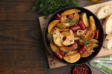 Delicious baked potato with thin dry smoked sausages in bowl, bread and spices on wooden table, flat lay. Space for text