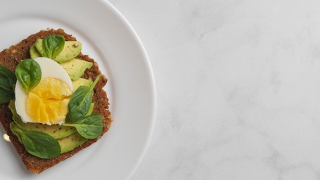 Photo of Tasty sandwich with boiled egg and avocado on white marble table, top view. Space for text