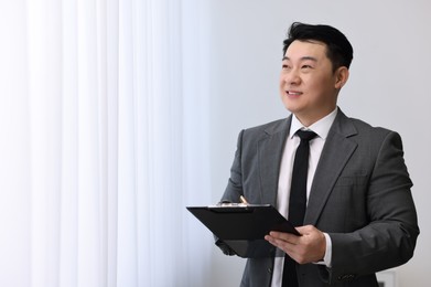 Photo of Portrait of happy notary with clipboard indoors, space for text