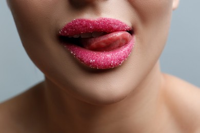 Closeup view of woman with lips covered in sugar on light grey background