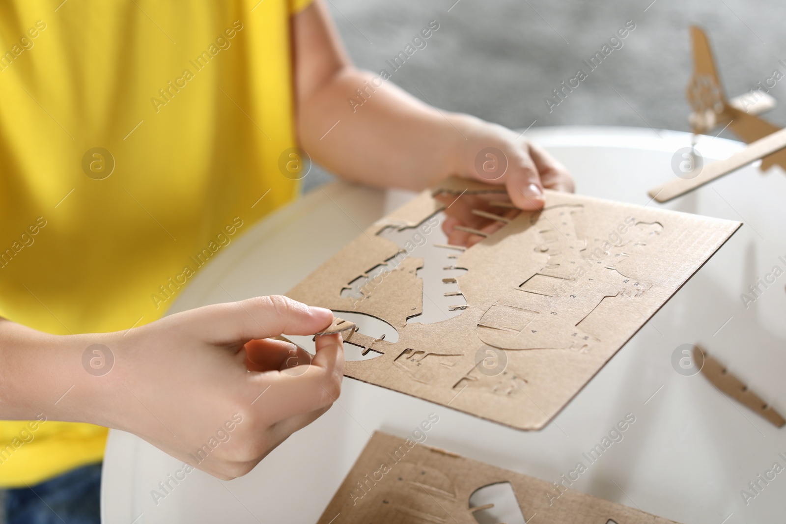 Photo of Little boy making carton toys at table indoors, closeup. Creative hobby